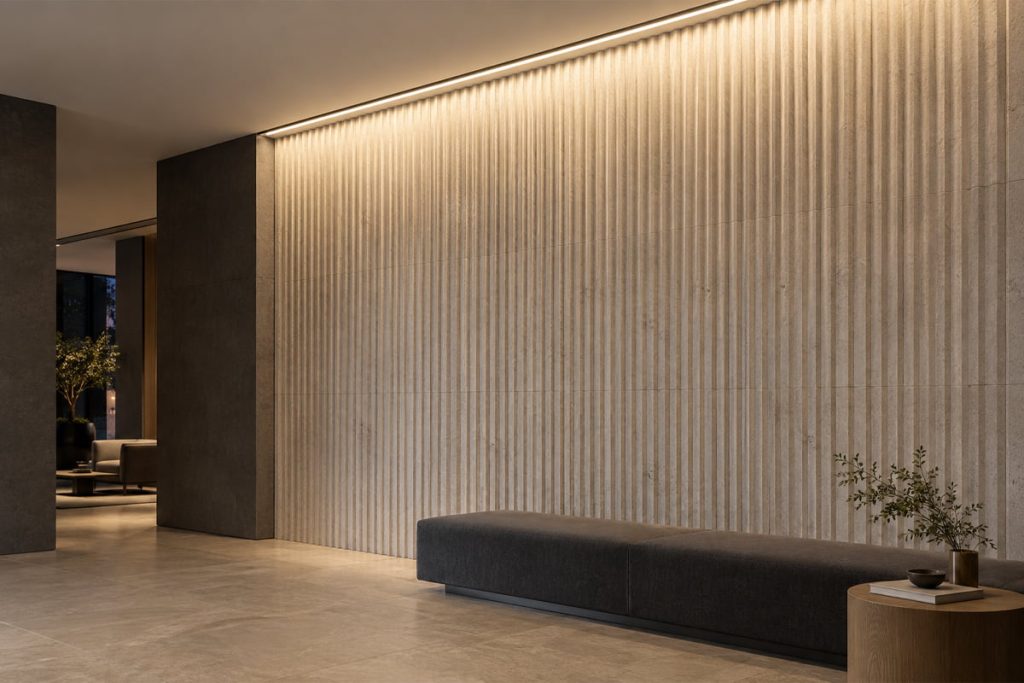 A recessed ceiling-edge linear LED light grazes a fluted stone wall above a charcoal bench.
